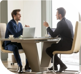 Twee professionals bespreken zakelijke aangelegenheden terwijl ze aan een tafel in een kantoor werken op een laptop
