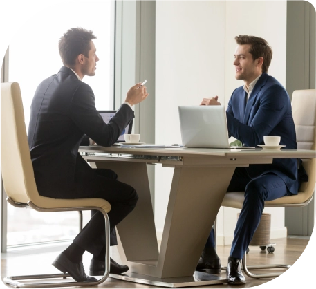 Twee professionals bespreken zakelijke aangelegenheden terwijl ze aan een tafel in een kantoor werken op een laptop